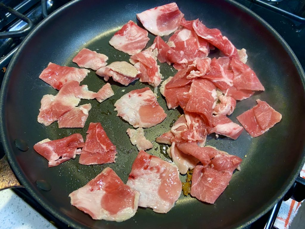 thinly sliced raw pork on a cooking pan