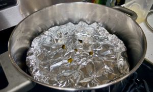homemade drop lid made of shaped foil with venting holes cut in the middle