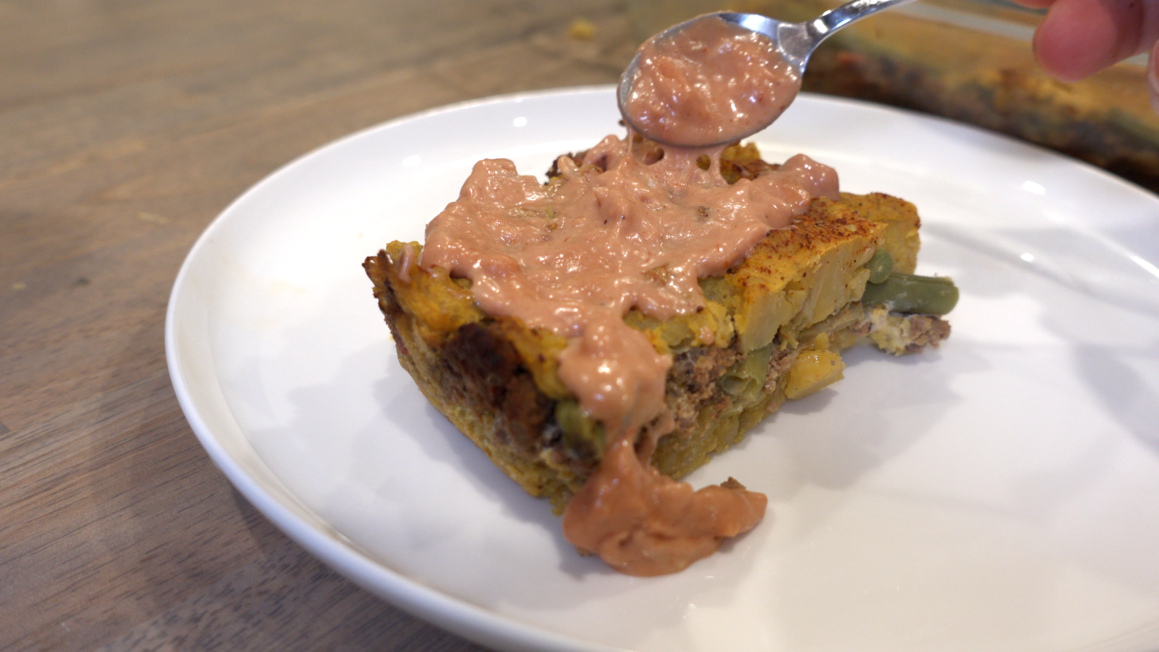 Rectangular slice of pastelon with garlic mayo ketchup spread on the top.